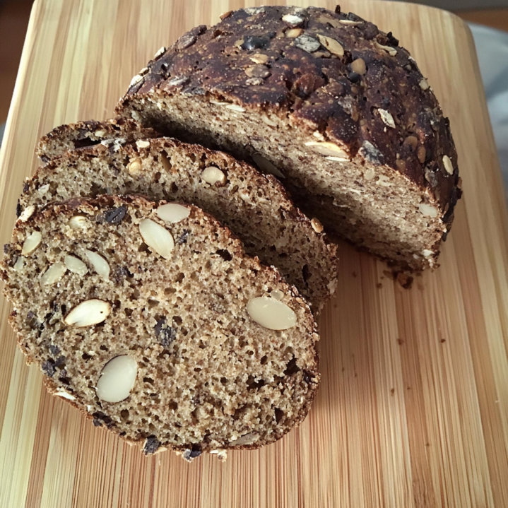 Aufgeschnittenes Brot ohne Kohlenhydrate mit Saaten und knuspriger Kruste auf einem Holzbrett