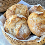 Frisch gebackene Sauerteigbrötchen mit knuspriger Kruste und lockerer Krume in einem Brotkorb.