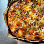 Frisch gebackene Sauerteig Focaccia mit Kirschtomaten, Rosmarin und goldbrauner knuspriger Kruste